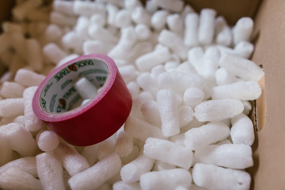 mushroom packaging - Close-up of red duct tape on packing peanuts in a cardboard box for shipping or moving.