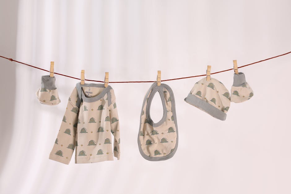 baby product packaging - Baby clothes set with cute patterns hanging on a line against a white background.