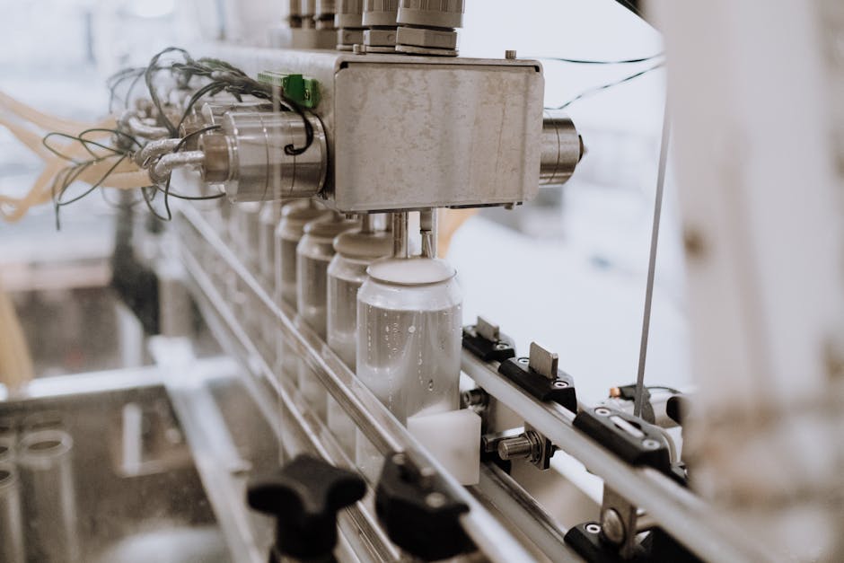 filling line optimization - Close-up of an automated can filling machine in a beverage production line.