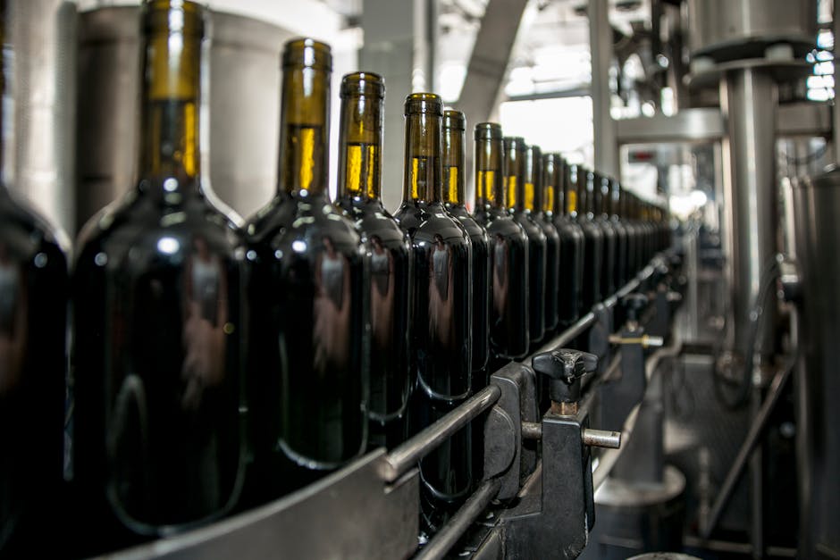 glass container specifications - Rows of wine bottles on a production line in an industrial setting.