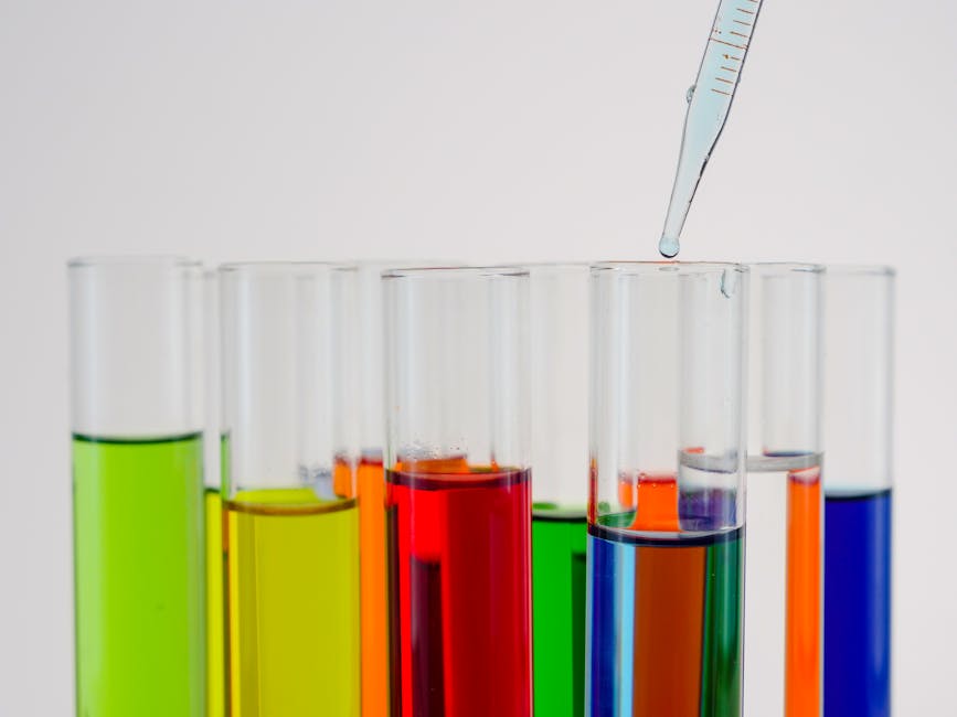 Close-up of colorful liquid in test tubes with a dropping pipette in a laboratory setting.
