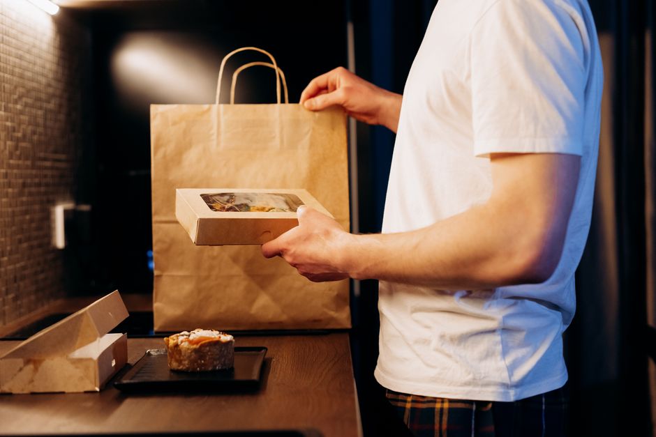 packaging industry news - Man unpacking a food delivery bag in a modern kitchen. Ideal for lifestyle or delivery themes.