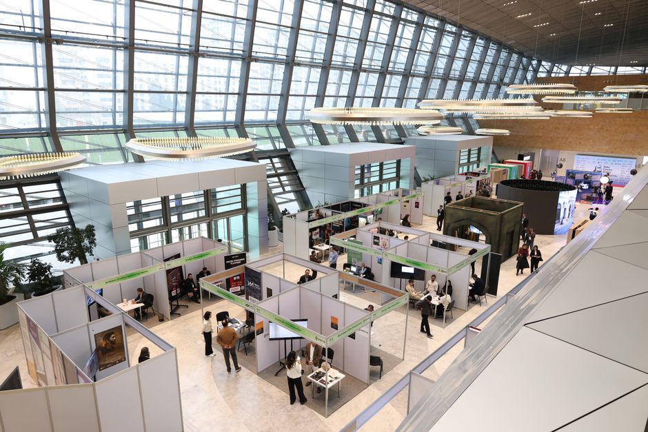 packaging industry news - A bustling trade show exhibition inside a modern hall with people networking and exploring booths.
