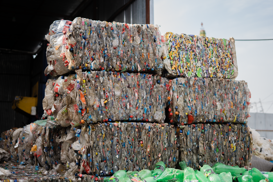 packaging industry news - Stacked compressed plastic bottles at a recycling facility, ready for processing.